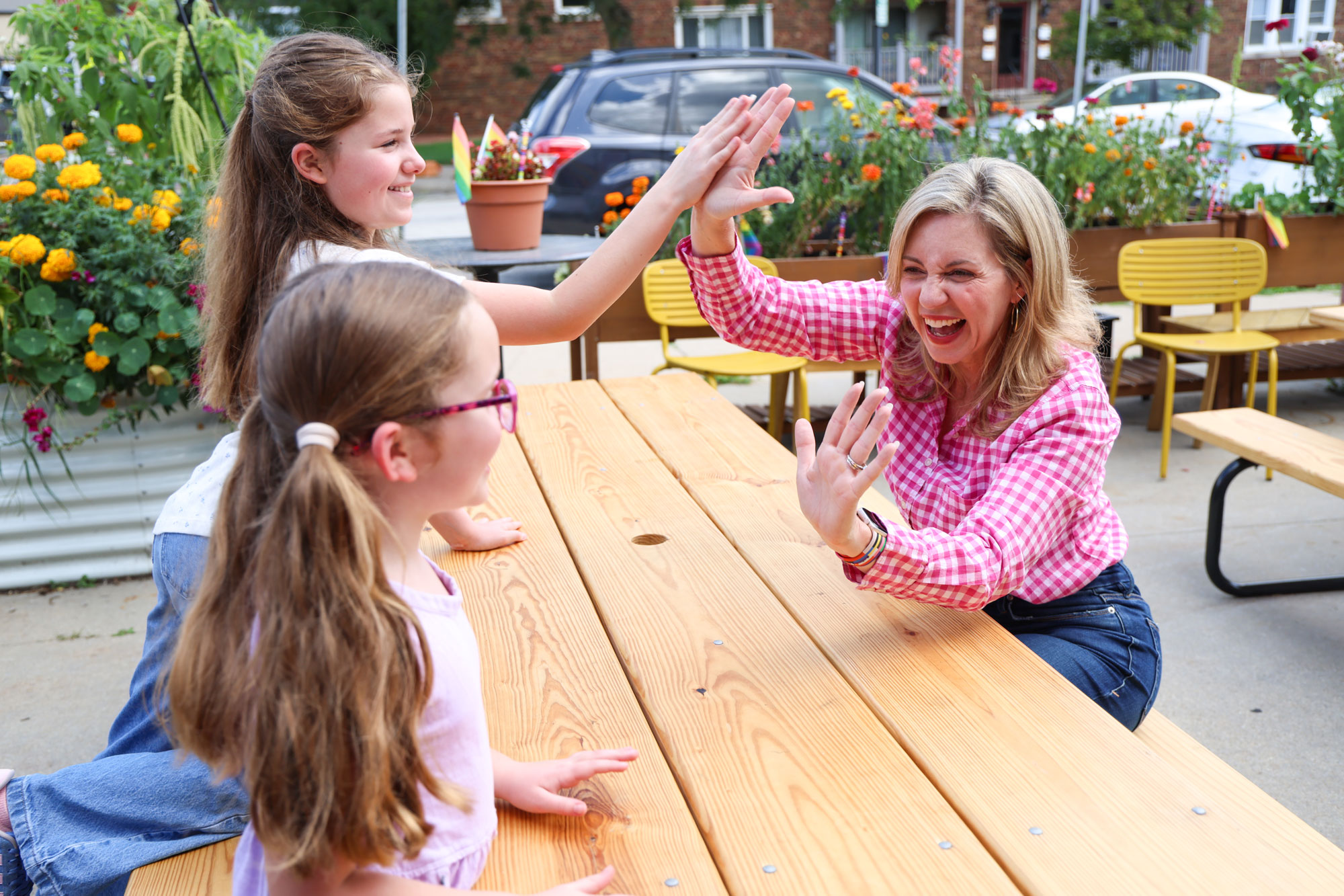 Robyn at a picnic table high-fiving two young girls